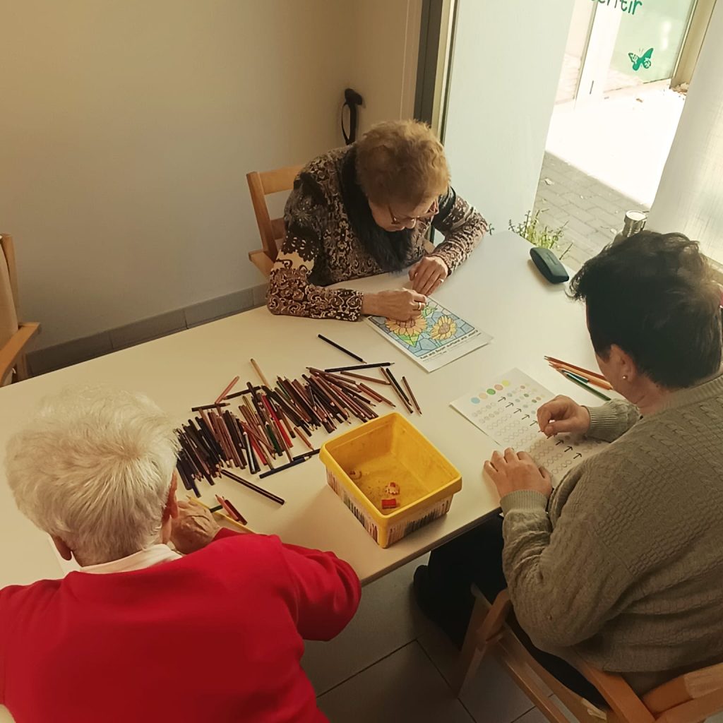 Usuarios realizando ejercicios cognitivos de coloreado y memoria en una mesa en el centro AFA Castalla y Onil.