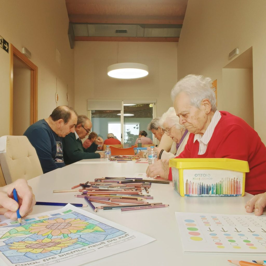 Usuarios coloreando fichas terapéuticas en una mesa alargada en AFA Castalla y Onil.