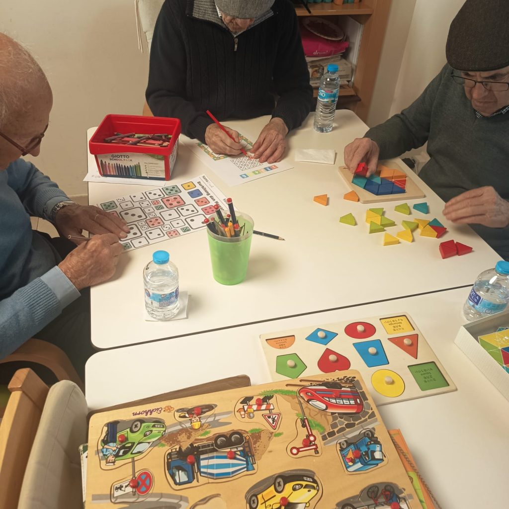 Usuarios realizando ejercicios cognitivos y manipulativos en una mesa en AFA Castalla y Onil.
